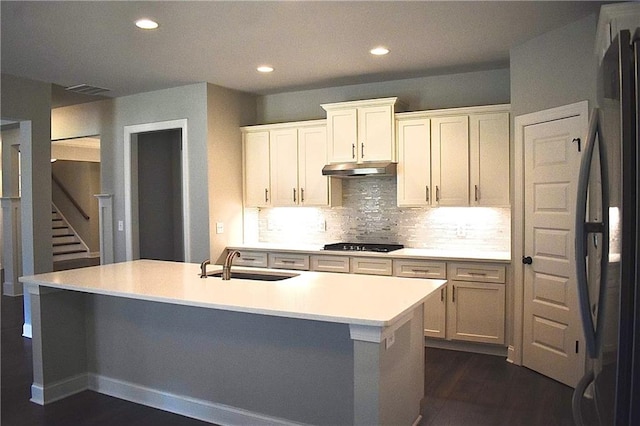 kitchen featuring white cabinets, an island with sink, sink, and black gas stovetop