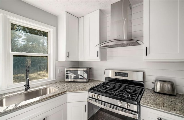 kitchen with sink, white cabinets, wall chimney exhaust hood, and stainless steel appliances