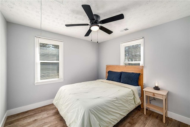 bedroom with ceiling fan, multiple windows, and wood-type flooring