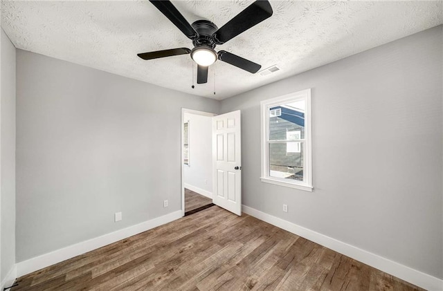 spare room featuring wood-type flooring, a textured ceiling, and ceiling fan