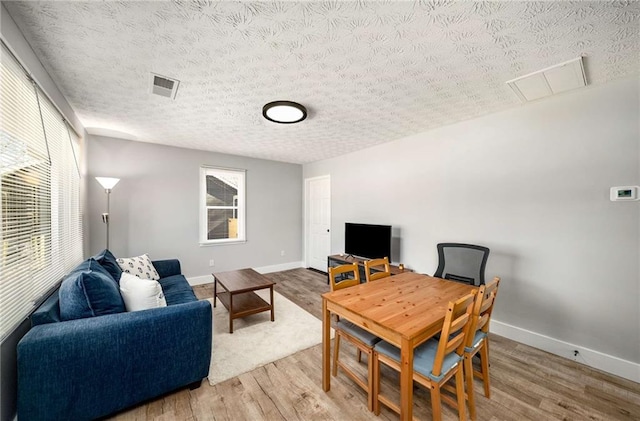 dining area featuring plenty of natural light, wood-type flooring, and a textured ceiling