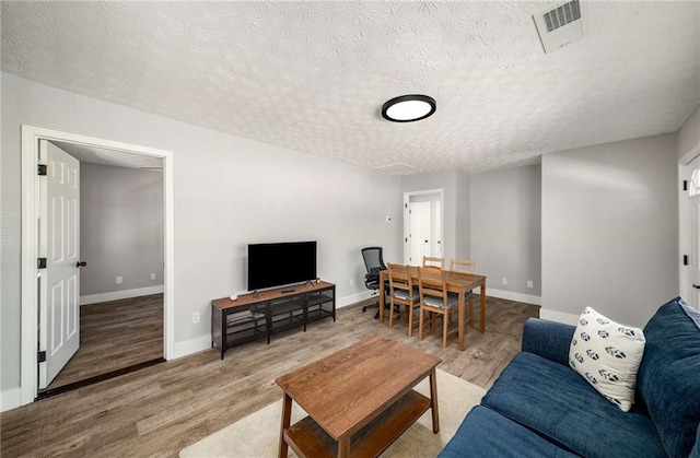 living room with light wood-type flooring and a textured ceiling