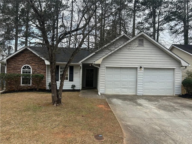 ranch-style home with a garage, concrete driveway, and a front yard