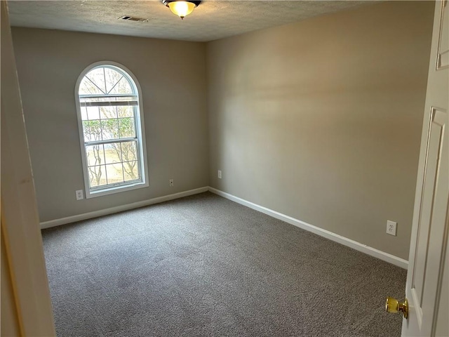 carpeted spare room with a textured ceiling, visible vents, and baseboards