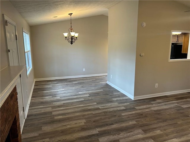 unfurnished dining area featuring baseboards, lofted ceiling, dark wood-style flooring, a textured ceiling, and a chandelier