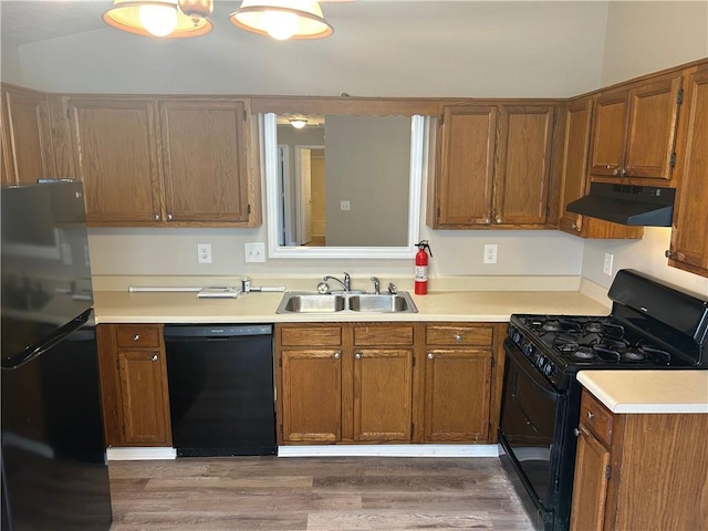 kitchen featuring black appliances, under cabinet range hood, light countertops, and a sink