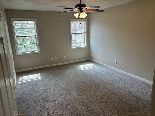 carpeted empty room with a textured ceiling, baseboards, visible vents, and a healthy amount of sunlight