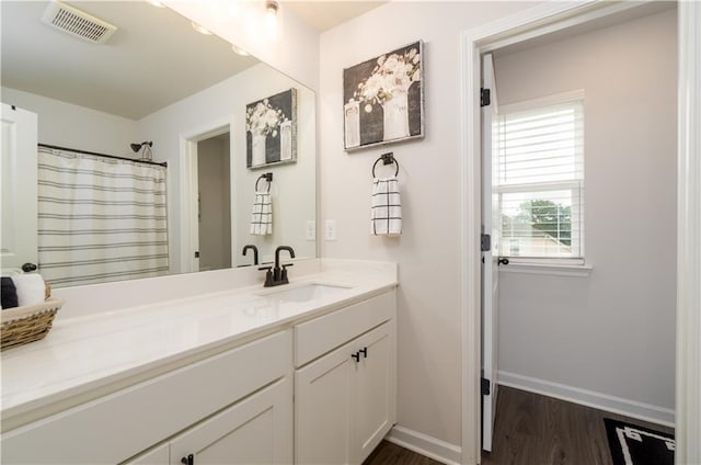full bath with baseboards, wood finished floors, and vanity