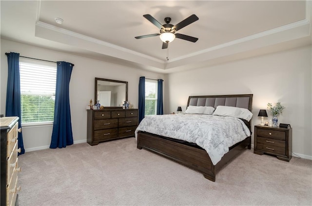 bedroom with a tray ceiling, crown molding, light carpet, baseboards, and ceiling fan