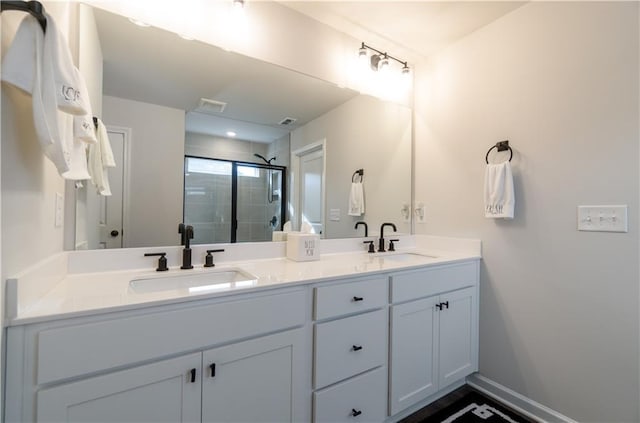 bathroom featuring a stall shower, double vanity, and baseboards