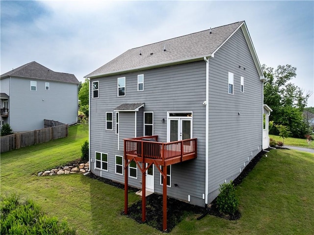back of property featuring a lawn, a deck, and a shingled roof
