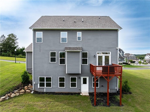 back of property featuring a yard, a wooden deck, and a shingled roof