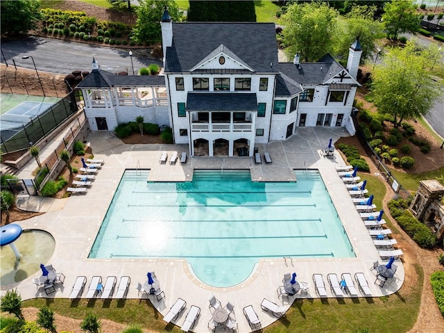 back of house with a balcony, fence, a patio area, a chimney, and a community pool