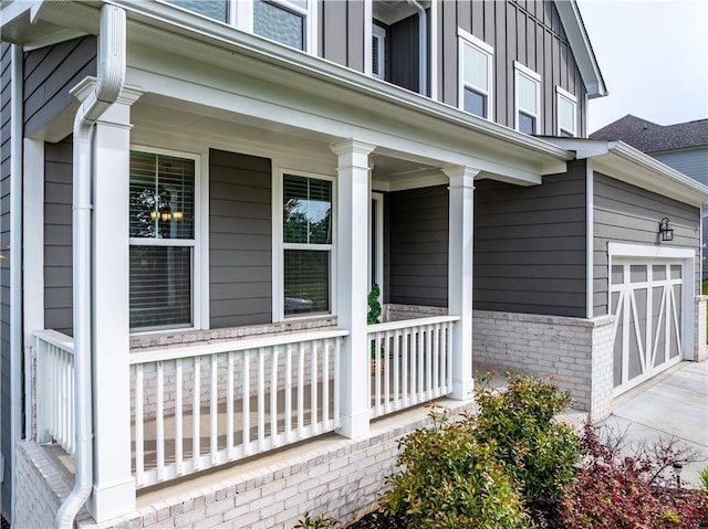 view of side of property featuring covered porch, brick siding, driveway, and board and batten siding