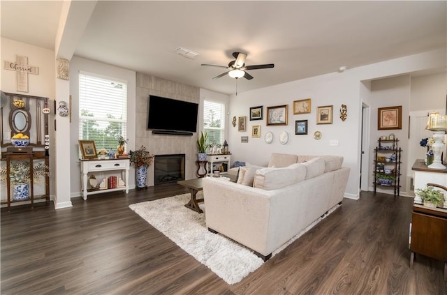 living area with a ceiling fan, a fireplace, dark wood-style flooring, and baseboards