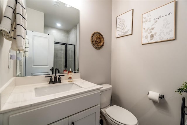 full bath featuring toilet, a tile shower, and vanity