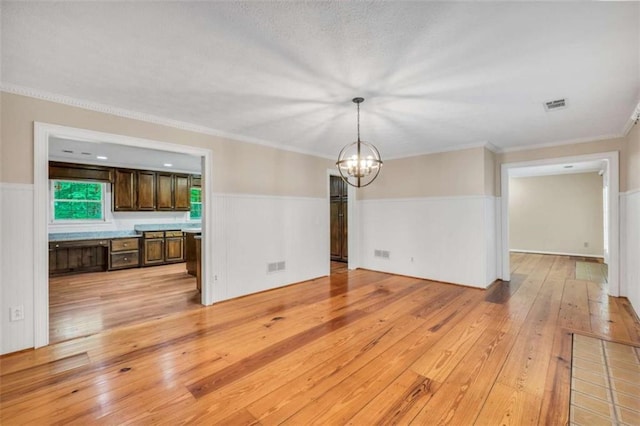 280 W Knight Rd W, Mcdonough, GA 30252 - unfurnished living room featuring a chandelier, light wood-style floors, crown molding, and a wainscoted wall