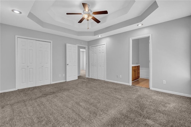 2551 Tolliver Dr, Ellenwood, GA 30294 - unfurnished bedroom featuring baseboards, two closets, a tray ceiling, and carpet floors