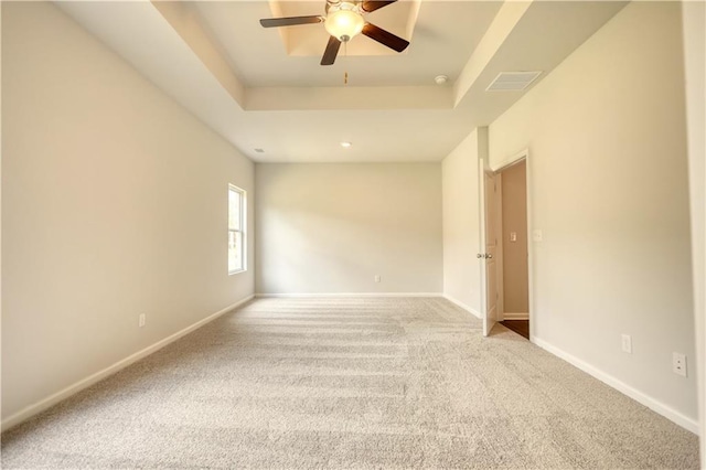 carpeted empty room featuring a raised ceiling and ceiling fan