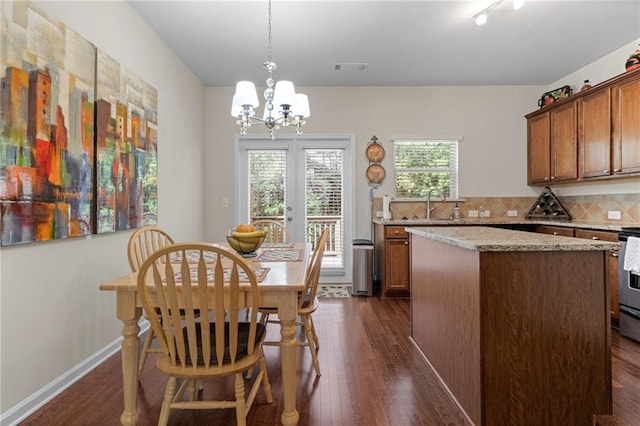 dining area with french doors, a notable chandelier, sink, and dark hardwood / wood-style floors