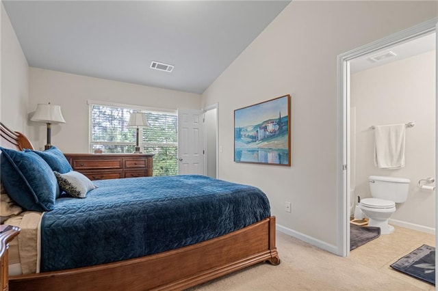 bedroom with light carpet, lofted ceiling, and ensuite bathroom