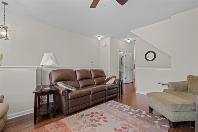 living area with wood finished floors, ceiling fan, baseboards, and a chandelier