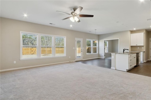 kitchen with light stone countertops, white cabinets, stainless steel dishwasher, open floor plan, and dark carpet