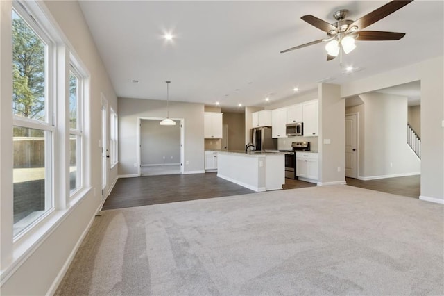 unfurnished living room with recessed lighting, dark carpet, stairway, and baseboards