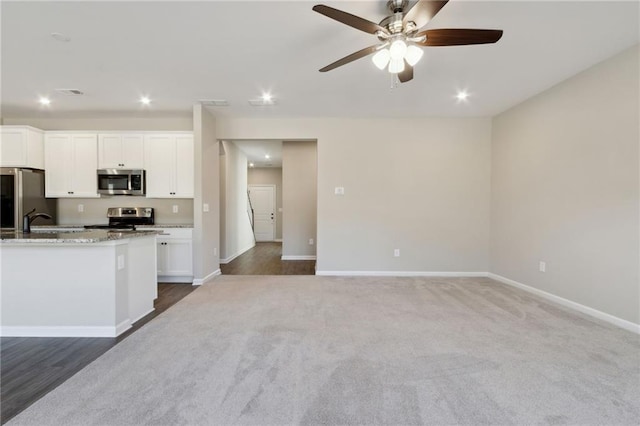 kitchen with white cabinets, carpet, baseboards, and stainless steel appliances