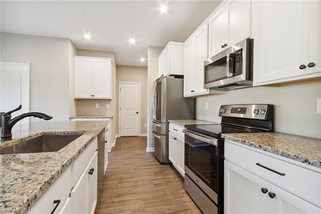 kitchen featuring light wood finished floors, recessed lighting, stainless steel appliances, white cabinetry, and a sink