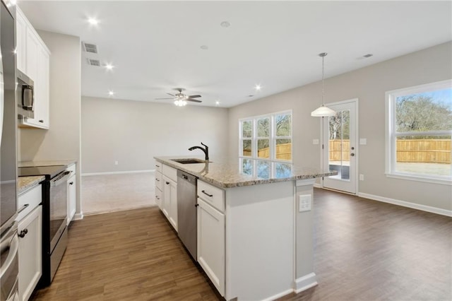 kitchen with dark wood finished floors, white cabinets, appliances with stainless steel finishes, and a sink