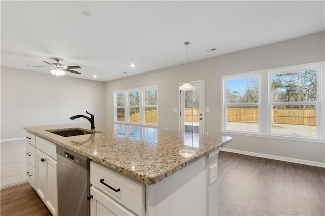 kitchen featuring light stone countertops, a sink, hanging light fixtures, white cabinets, and stainless steel dishwasher