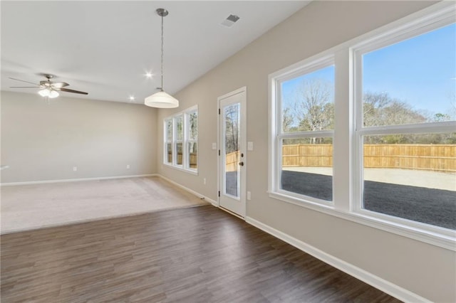 interior space with visible vents, a ceiling fan, dark wood-type flooring, and baseboards