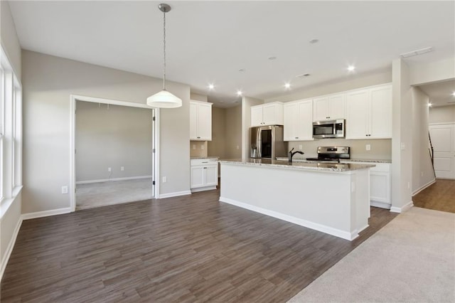 kitchen featuring dark wood finished floors, an island with sink, a sink, stainless steel appliances, and white cabinetry