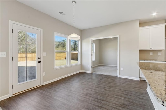 unfurnished dining area featuring visible vents, dark wood-type flooring, and baseboards