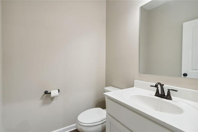 half bath with toilet, vanity, and baseboards