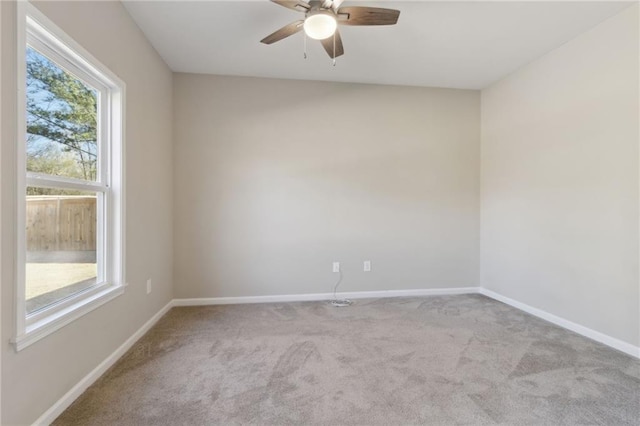 carpeted empty room featuring baseboards and ceiling fan