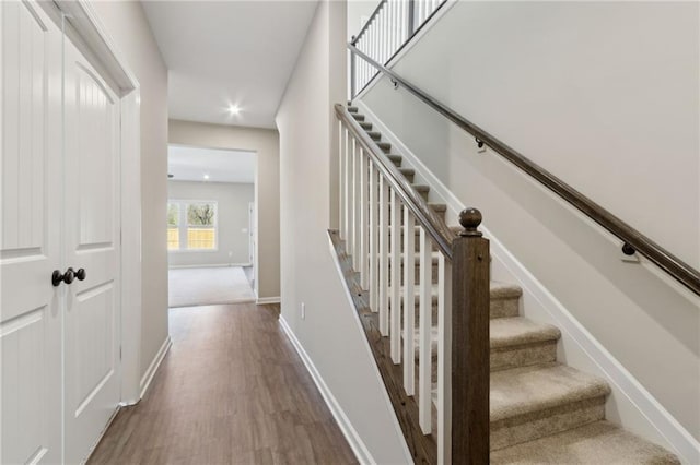 stairway featuring recessed lighting, wood finished floors, and baseboards