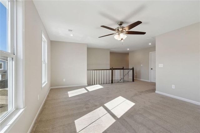 carpeted empty room featuring a wealth of natural light, visible vents, baseboards, and recessed lighting