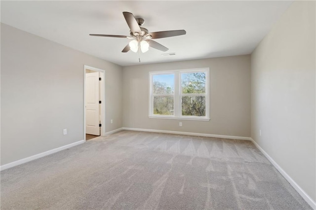 carpeted empty room featuring visible vents, a ceiling fan, and baseboards