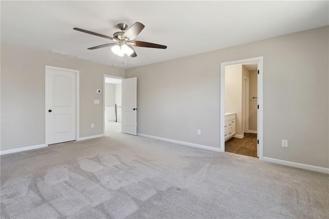 unfurnished bedroom with ensuite bath, carpet flooring, a ceiling fan, and baseboards