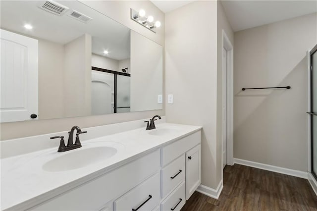 full bathroom with visible vents, a stall shower, wood finished floors, and a sink