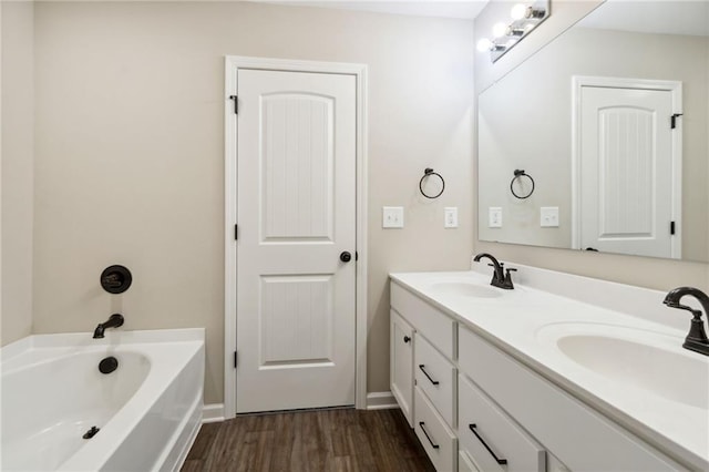 full bathroom featuring a sink, a tub to relax in, wood finished floors, and double vanity