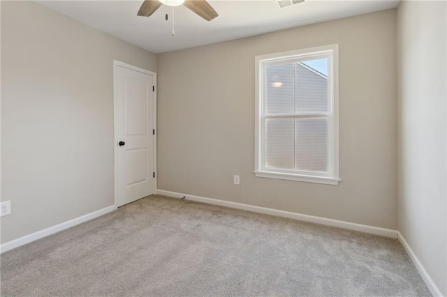 empty room with a ceiling fan, visible vents, light colored carpet, and baseboards