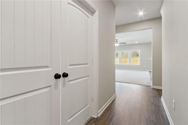 corridor featuring baseboards and dark wood-style floors