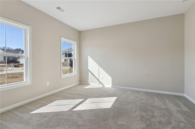 spare room featuring visible vents, baseboards, and light colored carpet