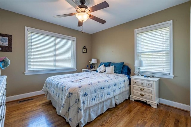 bedroom with ceiling fan, multiple windows, and hardwood / wood-style flooring