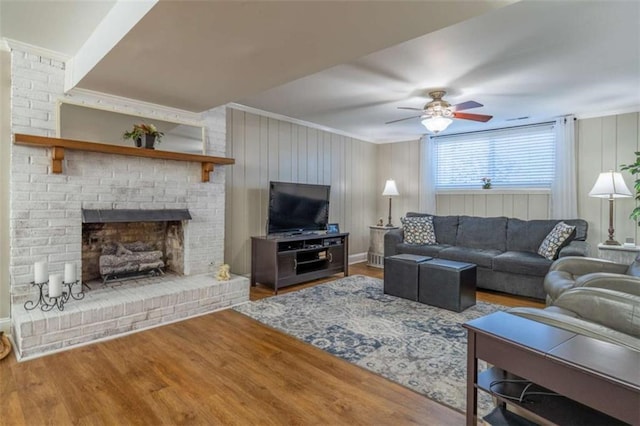 living room featuring ornamental molding, ceiling fan, hardwood / wood-style floors, and a fireplace