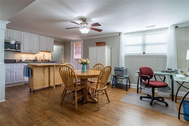 dining space featuring ceiling fan, hardwood / wood-style floors, and crown molding