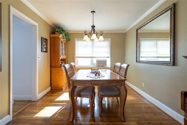 dining room featuring hardwood / wood-style flooring, ornamental molding, a notable chandelier, and a healthy amount of sunlight